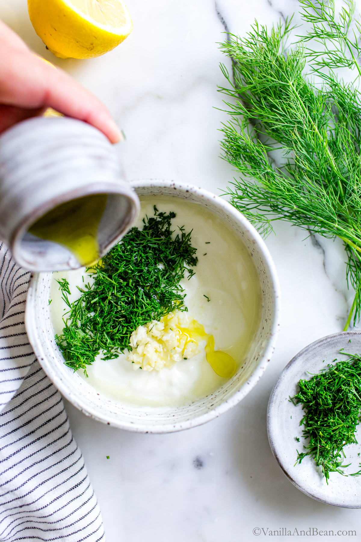 Adding ingredients to a bowl of yogurt Dill Sauce.