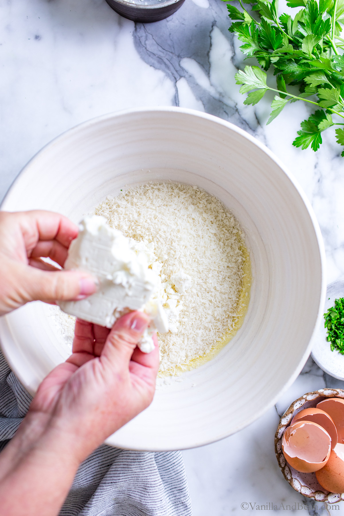 Crumbling feta into a large mixing bowl with panko and eggs.