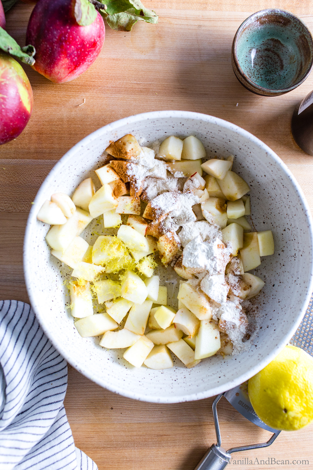 Diced apples with lemon zest, flour, and cinnamon in a bowl.